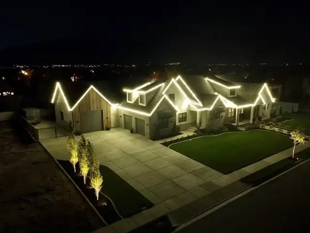 Warm white lights outline multiple roof peaks and small trees.