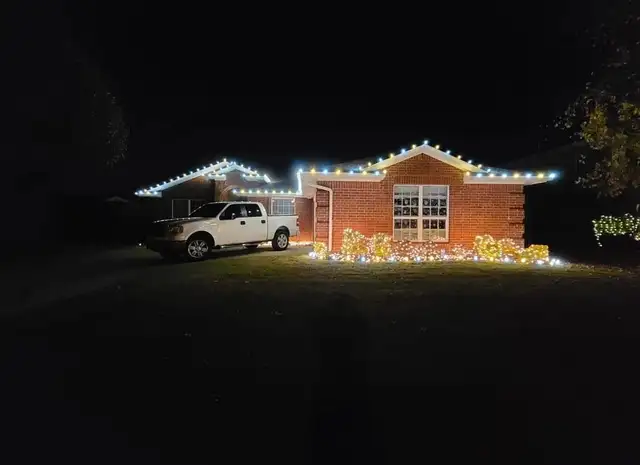 Warm lights outline a brick home and its front garden.