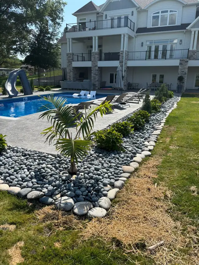 A long decorative stone bed with palms beside a pool.