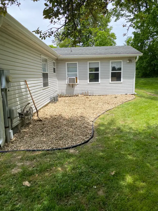 Decorative gravel covers a curved bed beside a home.
