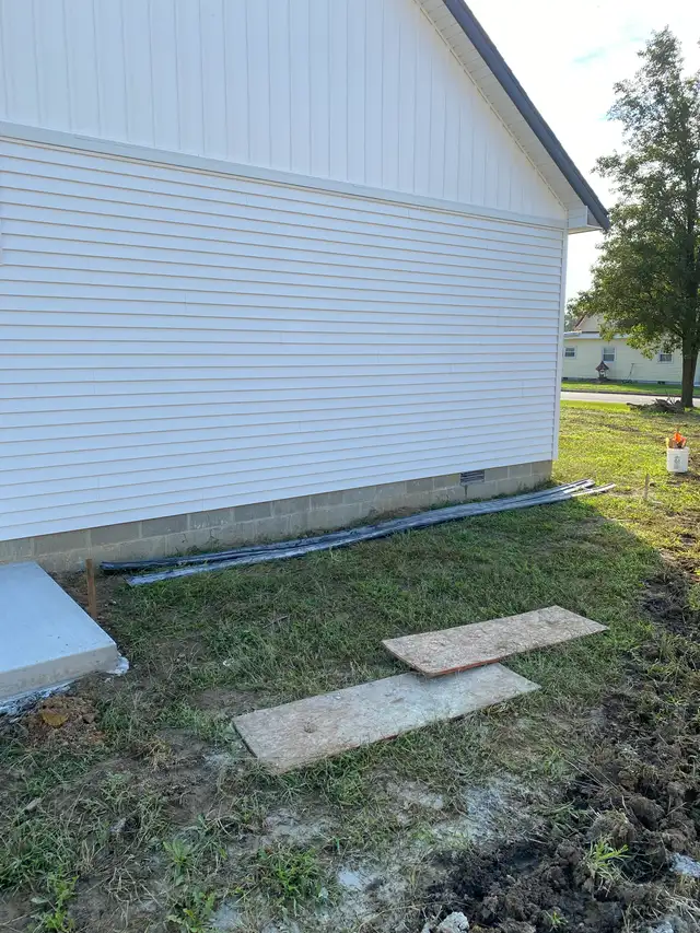 Prepared ground along the base of a white building.