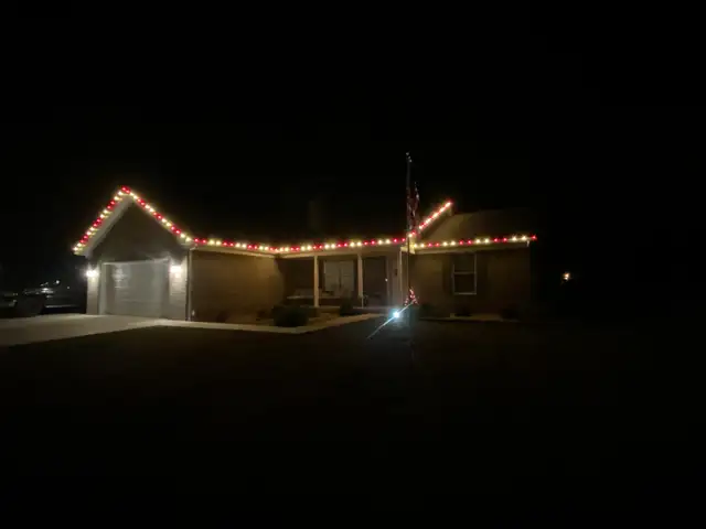 Red and warm white roofline lights on a home at night.