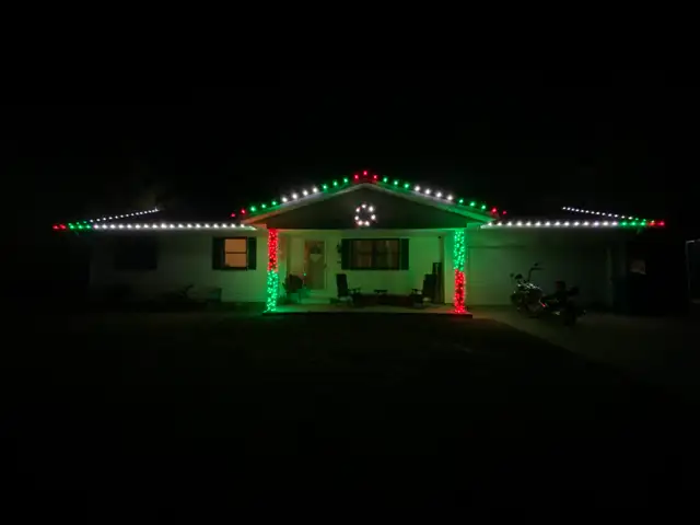 Red, green and white lights on a roofline and porch columns.