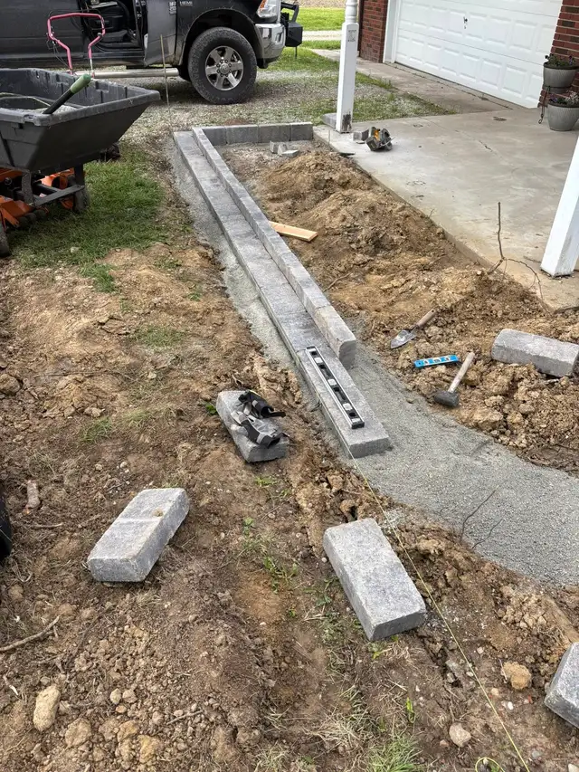 Garden border blocks being set beside a porch.