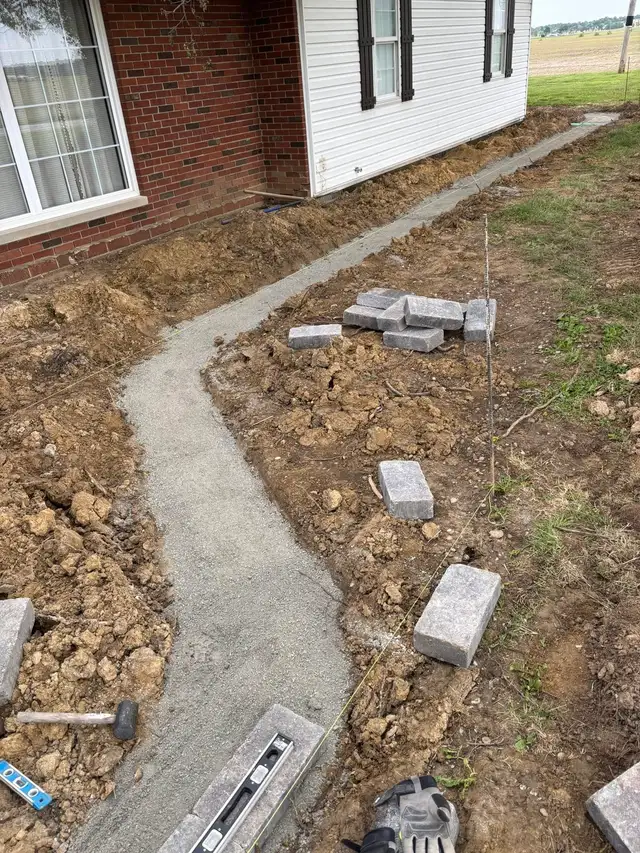 A curved garden-bed outline with edging blocks and tools.