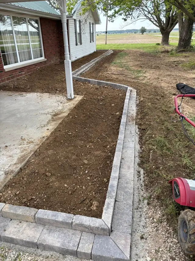 A garden bed edged with gray blocks beside a porch.