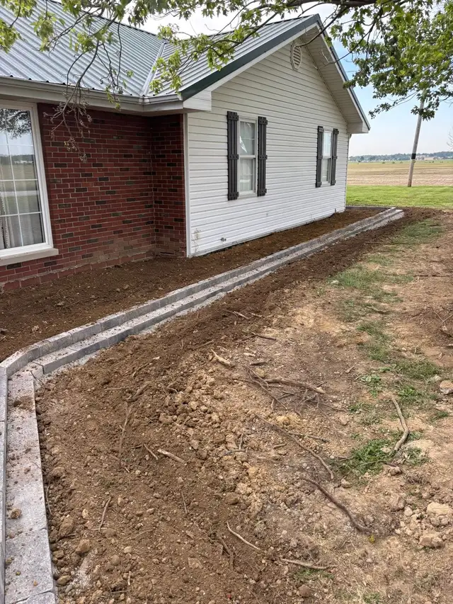 Gray garden edging follows a curved bed beside a home.